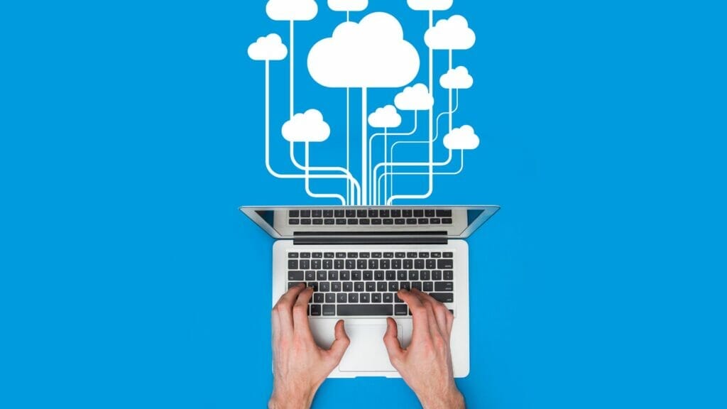 Eine Person, die eine Zahlungsabwicklungstransaktion auf einem Laptop durchführt, aus dem Wolken aufsteigen.