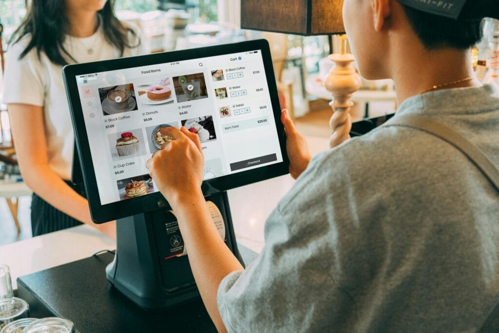 A customer using a touch screen system at a cafe counter for modern payment processing.